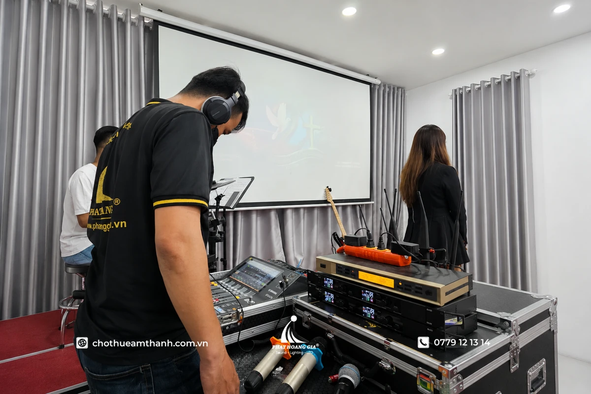 Kỹ thuật viên kiểm tra hệ thống âm thanh và tín hiệu micro trong quá trình tổng duyệt trước lễ khánh thành