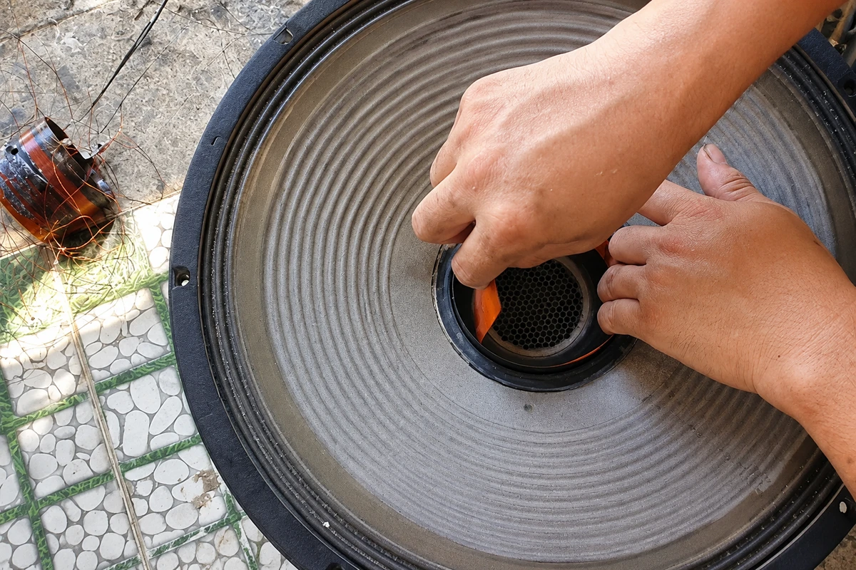 Kỹ thuật viên thực hiện căn tâm côn loa mới vào khe từ của củ loa bass trong quá trình thay côn loa bị cháy