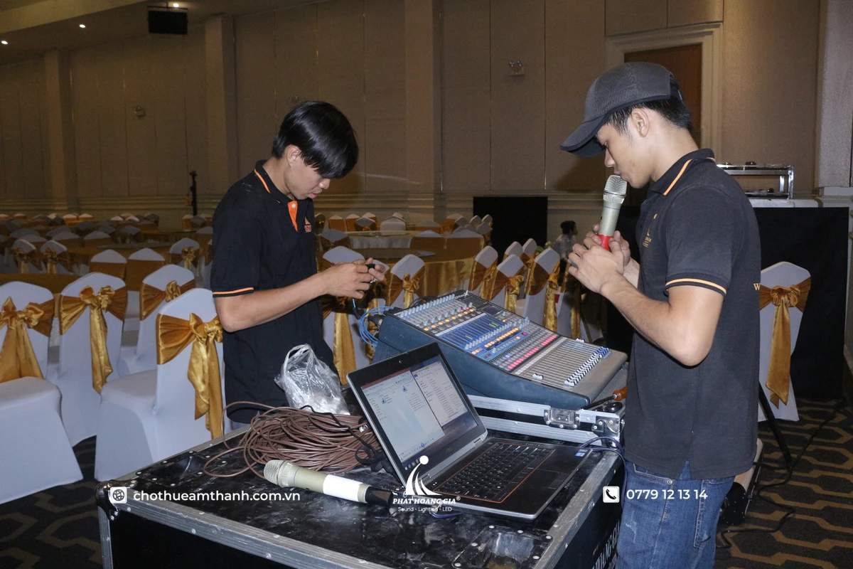 Kỹ thuật viên âm thanh kiểm tra micro, bàn mixer và hệ thống tín hiệu trong buổi tổng duyệt trước sự kiện doanh nghiệp