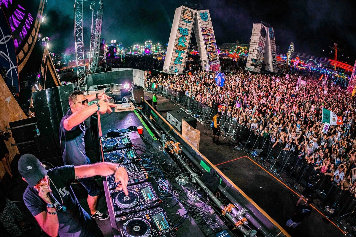Rave Là Gì Và Văn Hóa Lễ Hội Âm Nhạc Điện Tử EDM 13 DJ biểu diễn trên sân khấu Rave với bàn điều khiển chuyên nghiệp trước hàng nghìn khán giả hòa mình vào âm nhạc điện tử
