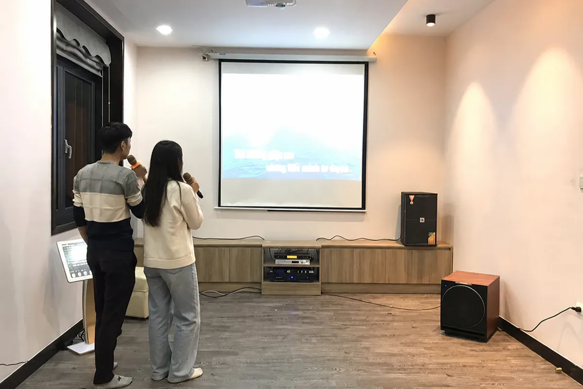 Top Bài Hát Karaoke Song Ca Nhạc Trẻ 2024 Hay Nhất 13 Cặp nam nữ hát karaoke song ca trước màn chiếu trong phòng giải trí gia đình