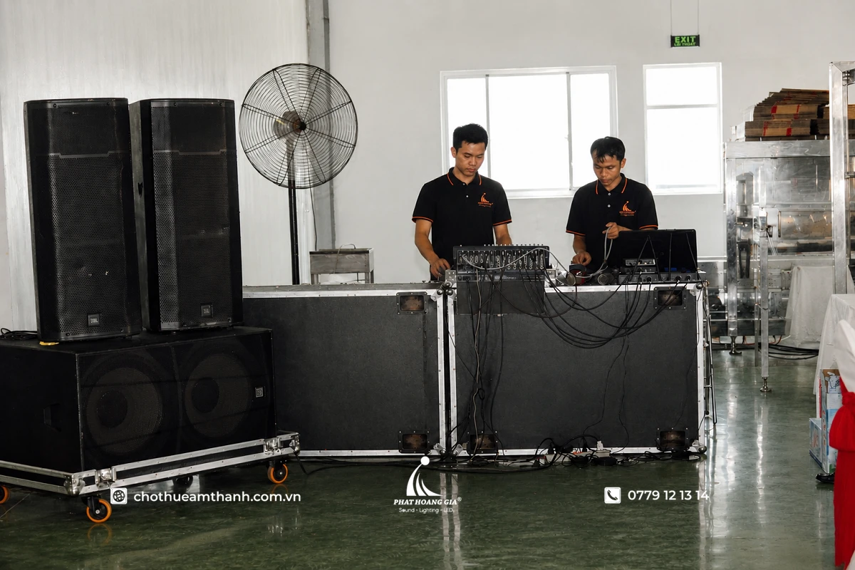 Kỹ thuật viên kiểm tra và cân chỉnh hệ thống loa công suất lớn trên bàn điều khiển âm thanh trước sự kiện 